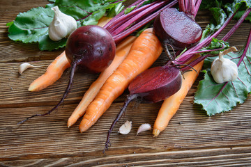 fresh organic carrot and beetroot with garlic on old wooden back