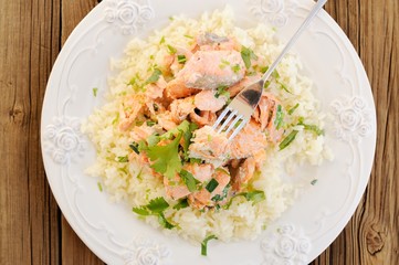 Salmon with rice, scallion and cilantro in white plate with fork