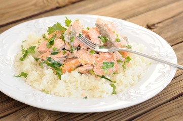 Salmon with rice, scallion and cilantro in white plate with fork