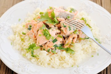 Salmon with rice, scallion and cilantro in white plate with fork