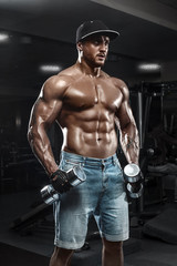 Fototapeta na wymiar Handsome muscular man with dumbbells working out in gym, doing exercise