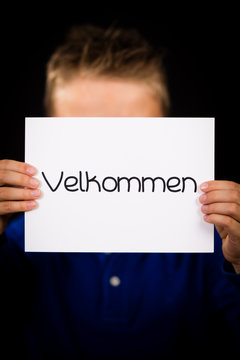 Child holding sign with Danish word Velkommen - Welcome
