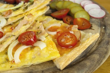 Homemade pizza, sliced on a wooden chopping boards, flavored with chilli peppers. Detail view.
