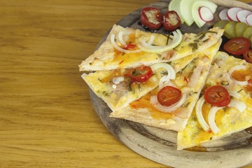 Homemade pizza, sliced on a wooden chopping boards, flavored with chilli peppers. Detail view.
