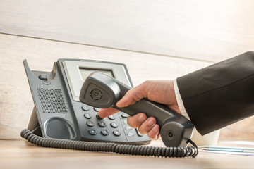 Closeup of a hand in a formal elegant suit dialing a telephone n