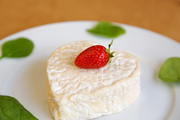 сыр с клубникой и салатом на белой тарелке