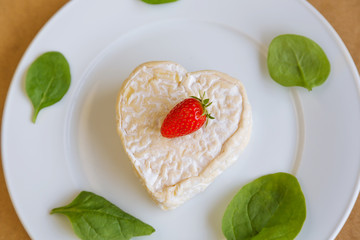 сыр с клубникой и салатом на белой тарелке