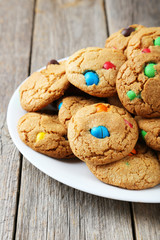 Cookies with colorful candy on plate on grey wooden background