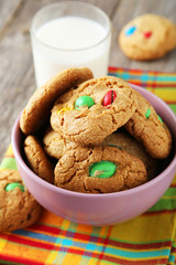 Cookies with colorful candy in bowl on grey wooden background