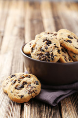 Chocolate chip cookies in bowl on brown wooden background
