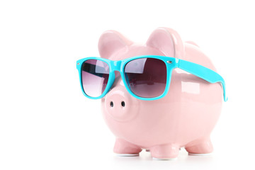 Pink piggy bank with glasses on white wooden background