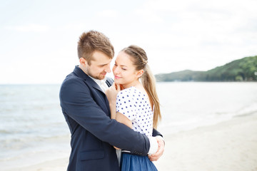 European couple relaxing on the sea beach hugging each other and talking