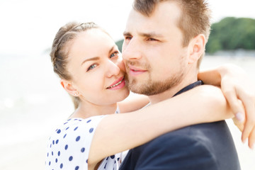 European couple relaxing on the sea beach hugging each other and talking