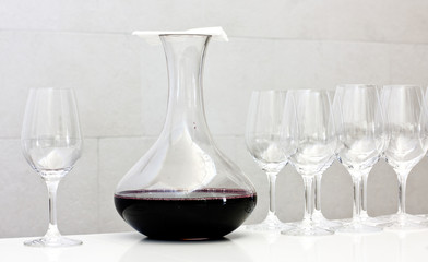 Wine tasting: decanter of red wine covered by napkin and row of glasses