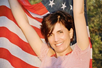 beautiful young woman with arms raised and the American flag behind