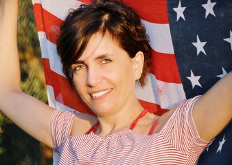 beautiful young woman with arms raised and the American flag behind