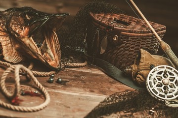 Fishing tools and pike's head on a wooden table