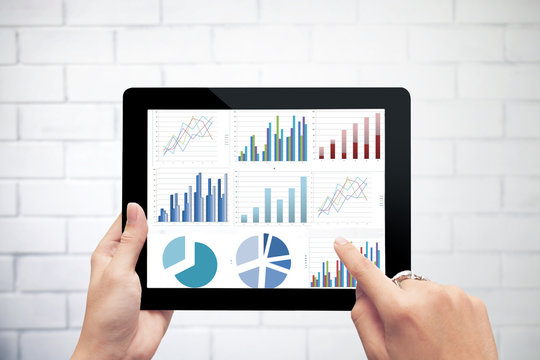 Close Up Hand Holding Digital Tablet With Analyzing Graph Agains