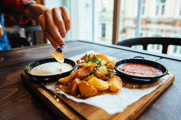 A woman eating a baked potato with sauce.