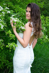 portrait of pretty woman in wedding dress in blooming summer gar