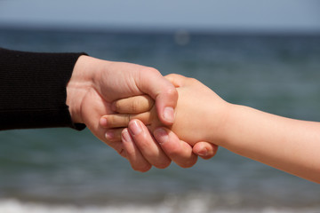 Frau hält reicht einem Kind die Hand