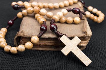 rosary and prayer book on a dark background