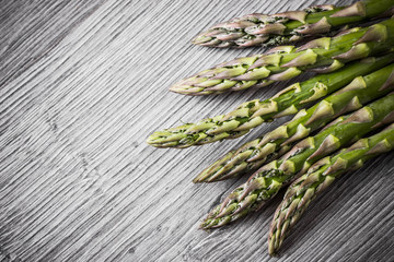 Raw, fresh asparagus on gray wood.