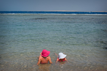 Two women in hats lie on the sea