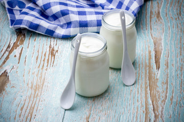 Two yogurt glass on wooden plate with spoon