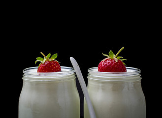 Two glass yogurt with strawberries on black