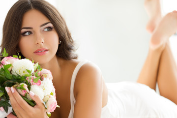 Obraz na płótnie Canvas Beautiful bride in white lingerie holding nuptial bouquet