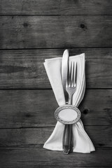 Messer und Gabel mit weißer Serviette auf Holz grau