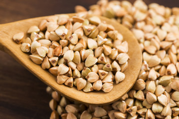 Buckwheat with a spoon on a wooden boards background