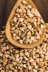 Buckwheat with a spoon on a wooden boards background
