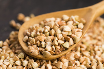 Buckwheat with a spoon on a wooden boards background