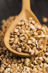 Buckwheat with a spoon on a wooden boards background