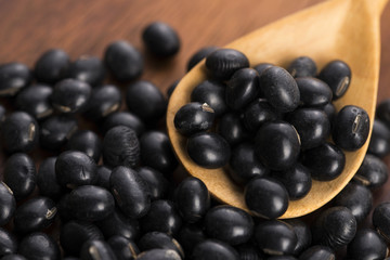 A lot of black soybeans on wooden background