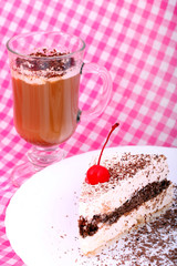 piece of chocolate cake and cup of cappuccino on white plate on checkered table-cloth
