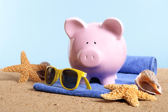 Piggy Bank or piggybank standing on a sunny tropical beach with towel holiday vacation retirement saving money plan photo