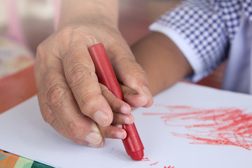 Grandma's hand holding child hand drawing with crayon,soft color