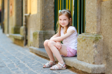 Adorable little girl sitting on a doorstep