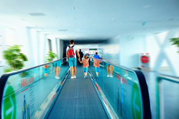 father and son moving on escalator after arrival in international airport