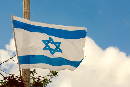 White and blue flag of Israel over the clouds in sky
