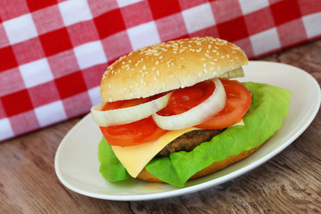 Cheeseburger with red and white checkered cloth in the background

