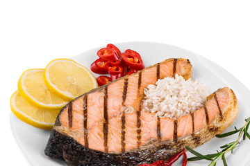 Grilled salmon steak with vegetables on plate.