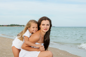 Happy beautiful mother and daughter enjoying beach time