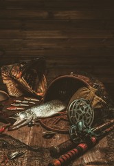 Fishing tools and fresh pike on a wooden table