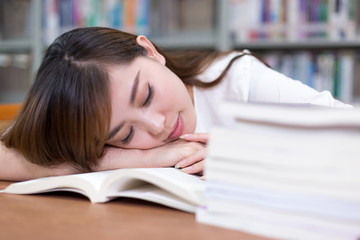 Beautiful asian femle student take nap in library during studyin