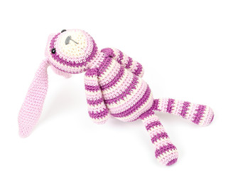 Knitted rabbit toy is sitting and looks up