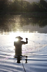 Silhouette if a fisherman and fishing net in the water